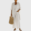 Woman wearing a three piece linen set with open duster, singlet and straight-leg pants