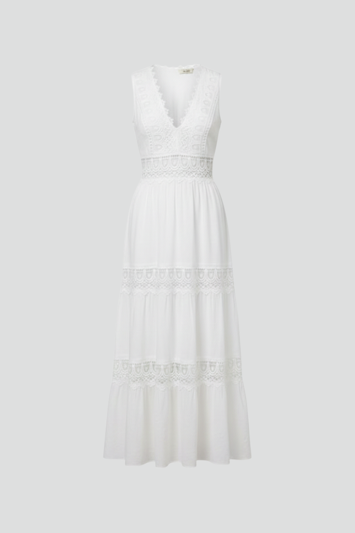 Woman wearing a white sleeveless lace maxi dress with V-neck and tiered skirt
