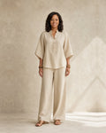 Woman wearing a wide leg two piece set with a band-collar button top and wide elbow sleeves
