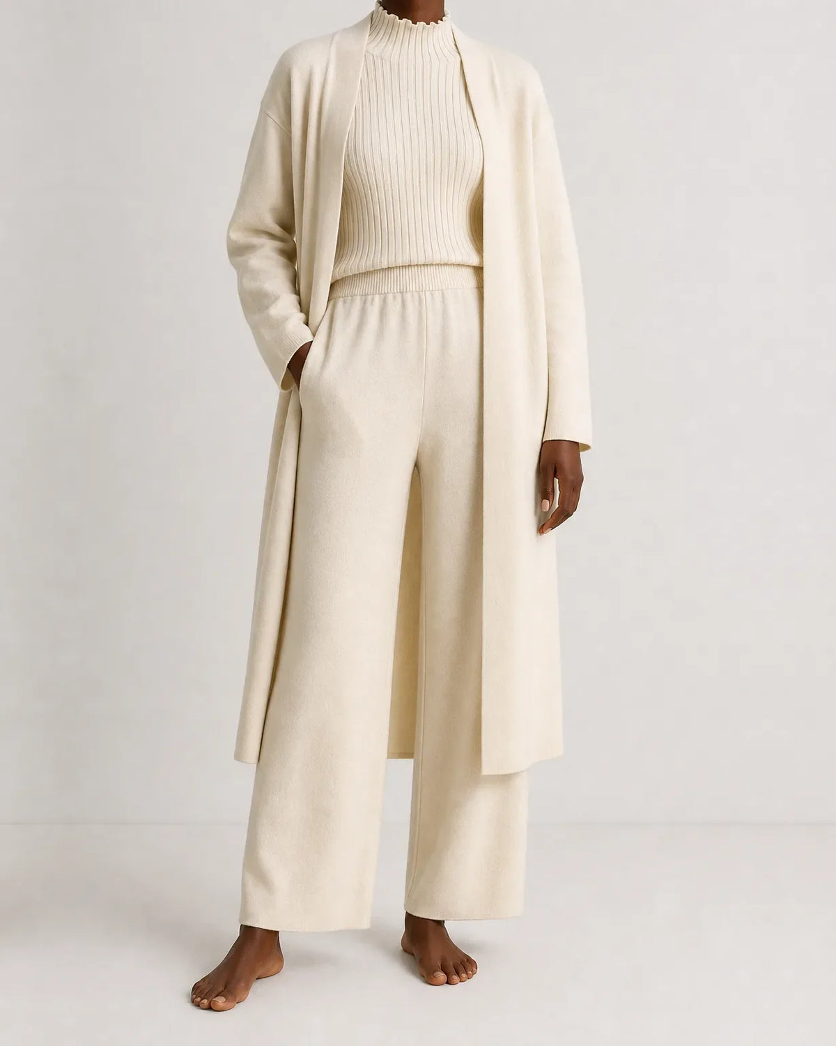 Woman wearing a three piece knit set with longline cardigan, ribbed mock-neck top and wide leg pants