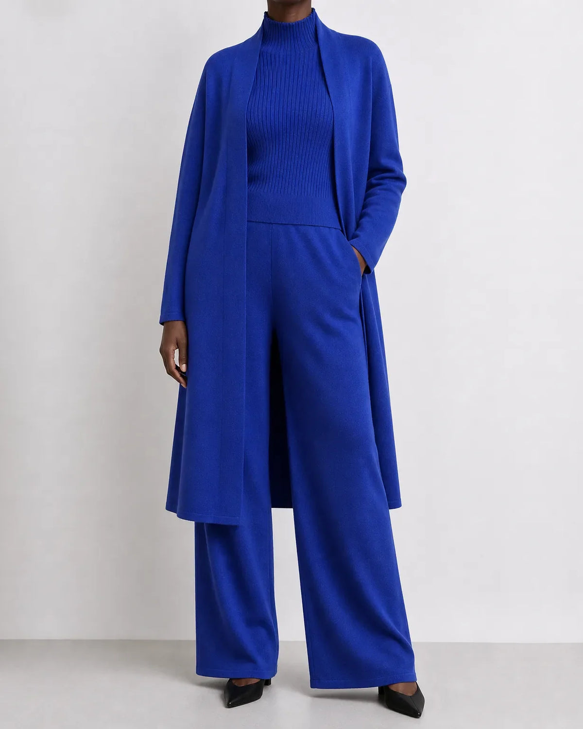 Woman wearing a three piece knit set with longline cardigan, ribbed mock-neck top and wide leg pants - view 4