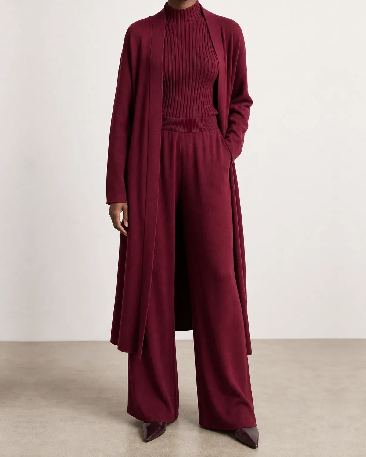 Woman wearing a three piece knit set with longline cardigan, ribbed mock-neck top and wide leg pants - view 7