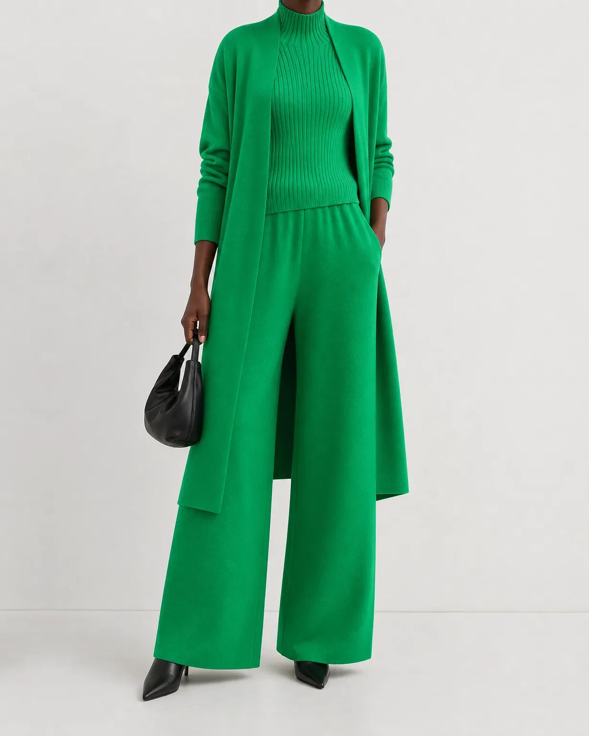 Woman wearing a three piece knit set with longline cardigan, ribbed mock-neck top and wide leg pants - view 9