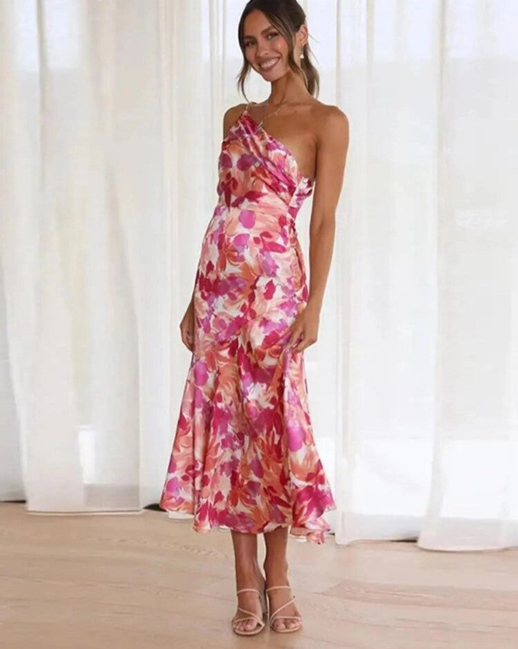 Woman wearing a one-shoulder floral print satin midi dress with draped bodice and fluted hem